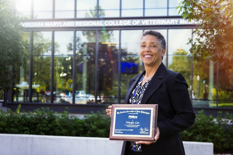 Person holding a plaque in front of the VMIA building at VMCVM.