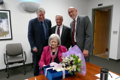 Shelley Duke receiving flowers and gifts in a board room.
