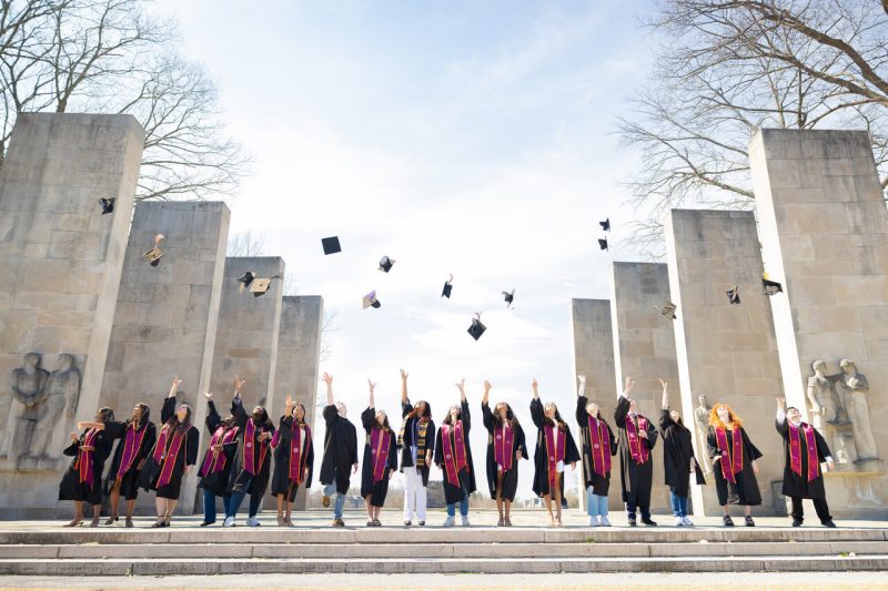 University Libraries student employees throwing their graduation caps at the Pylons